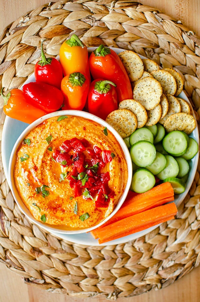 A serving platter with hummus, crudites and crackers