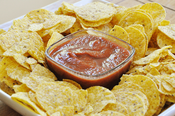 homemade salsa in a bowl surrounded by yellow corn chips