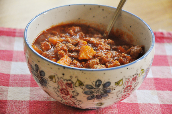 Slow cooker sweet potato chili in a floral bowl on a red checked napkin.