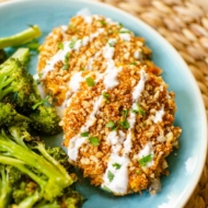 Closeup of a serving of salmon patties on a plate with broccoli and tartar sauce.
