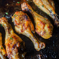 Cooked crispy chicken drumsticks on a baking sheet.