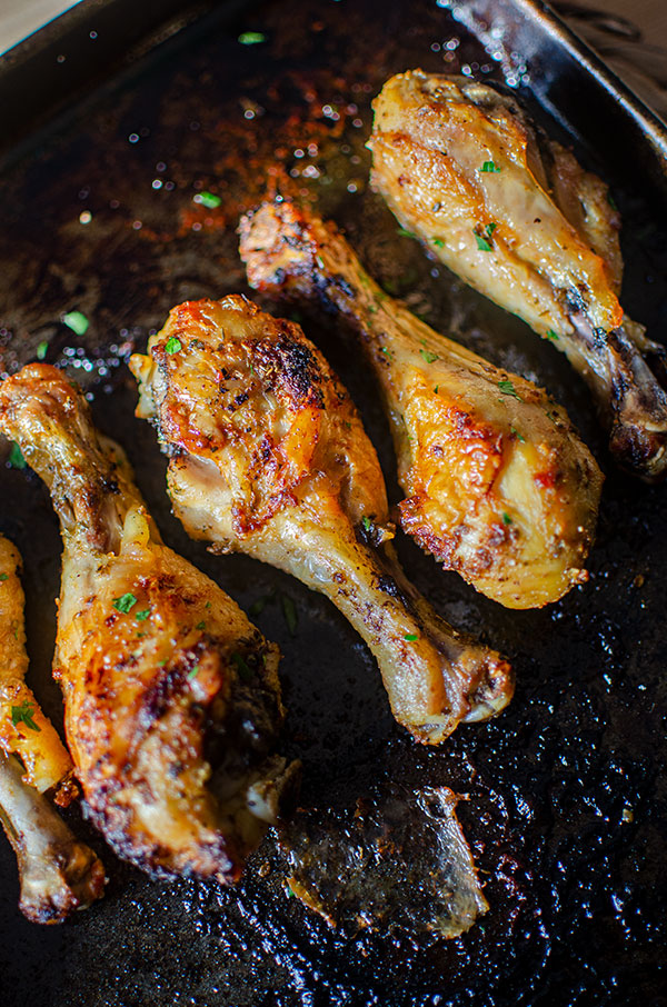 Cooked crispy chicken drumsticks on a baking sheet.