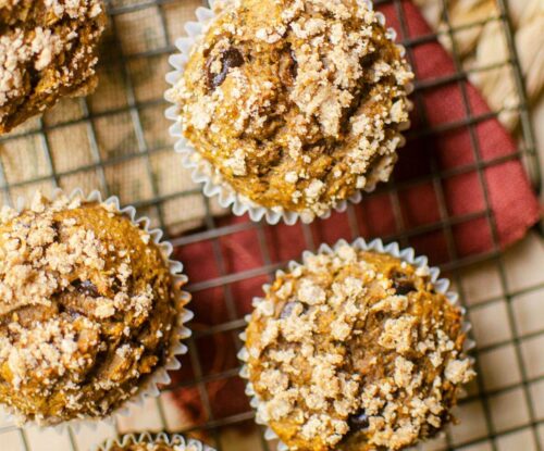 Closeup of banana pumpkin muffins on a cooling rack with a burgundy napkin.