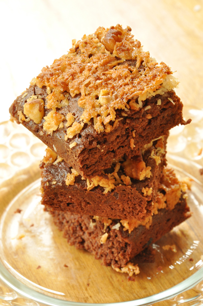 A stack of homemade brownies with coconut topping on a plate