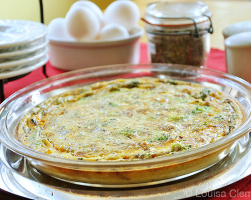 Crustless spinach quiche on a plate with eggs and herbs in the background