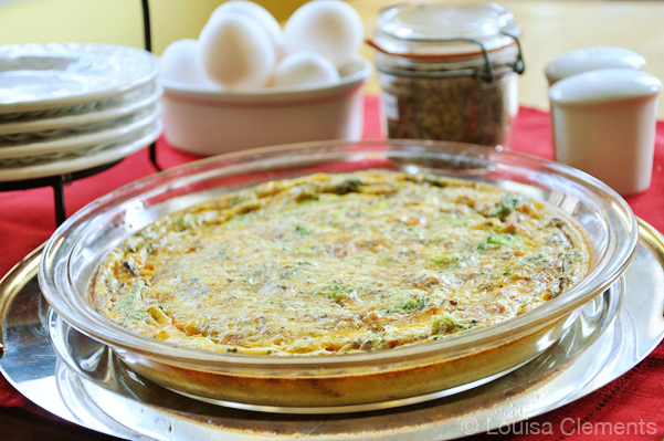 Crustless spinach quiche on a plate with eggs and herbs in the background