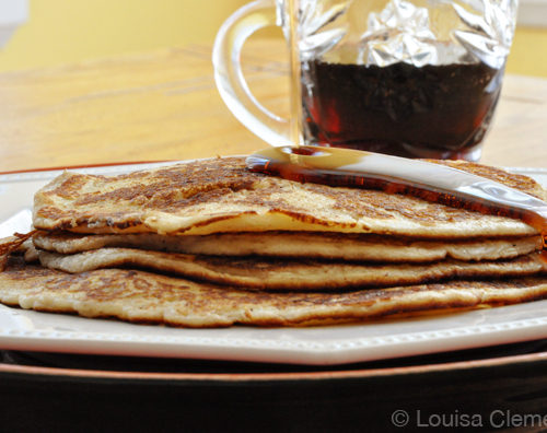 A stack of thin French Canadian pancakes with a drizzle of maple syrup