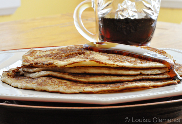 A stack of thin French Canadian pancakes with a drizzle of maple syrup