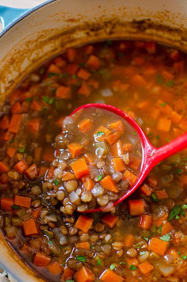 A big pot of lentil soup with a ladle spooning some out.