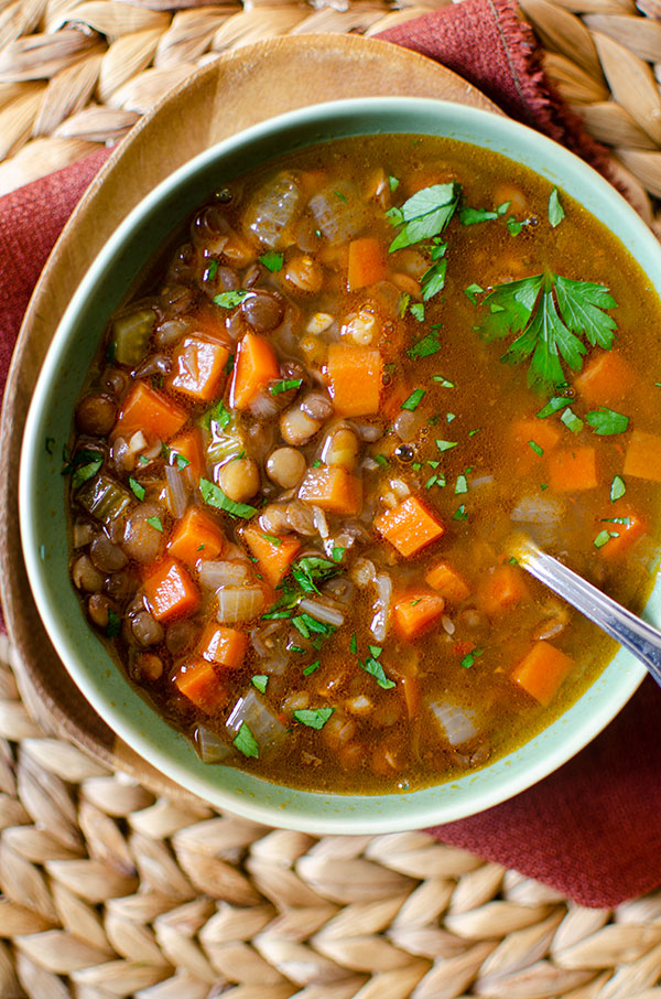 Mediterranean lentil soup in a green bowl on a burgundy napkin.