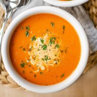 Closeup of soup in a white bowl on a grey napkin.