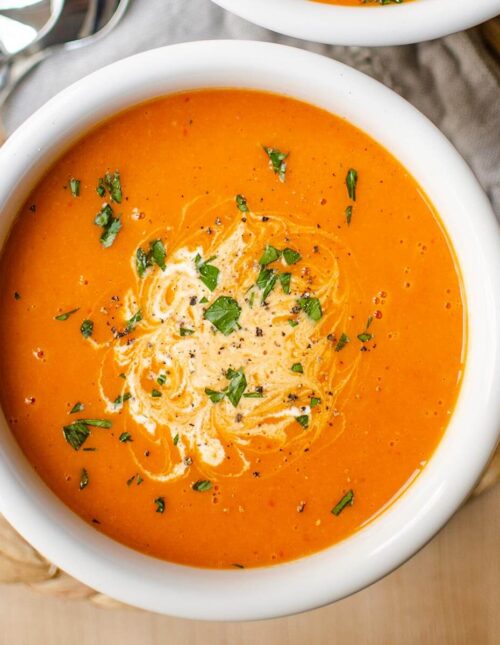 Closeup of soup in a white bowl on a grey napkin.