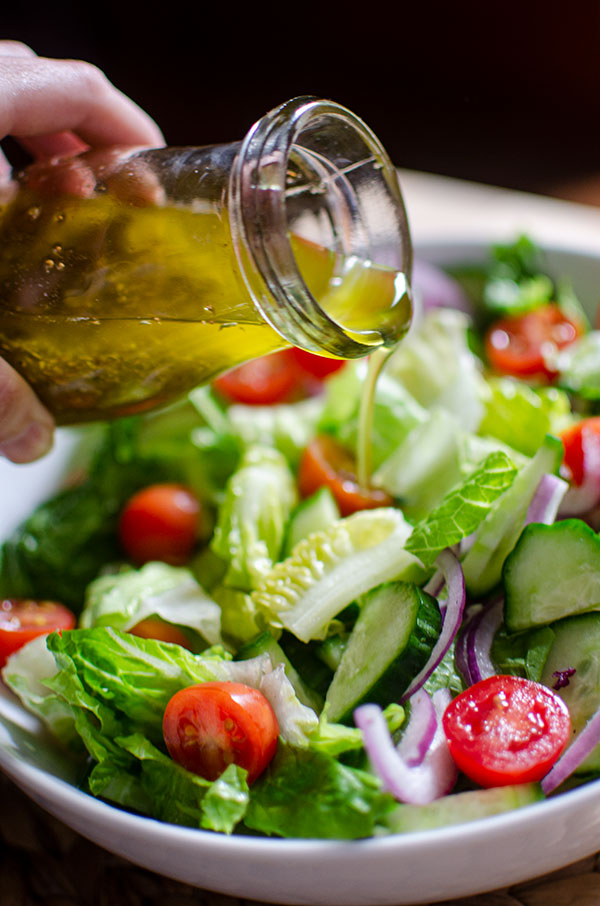 Closeup of vinaigrette being poured on the salad.