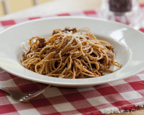 A bowl of basil garlic spaghetti sauce on a red checkered napkin