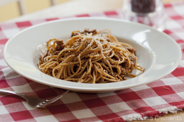 A bowl of basil garlic spaghetti sauce on a red checkered napkin