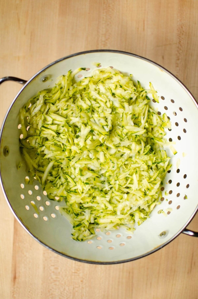 Shredded zucchini in a strainer.