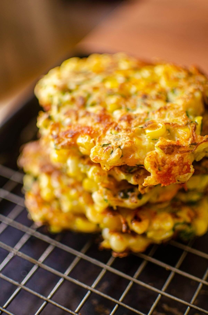 A stack of cooked fritters on a wire rack on a baking sheet.