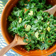 Kale avocado salad in a wooden bowl on an outdoor table.