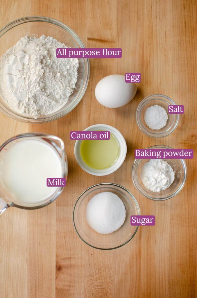 Ingredients for pancakes in bowls on a wooden board.