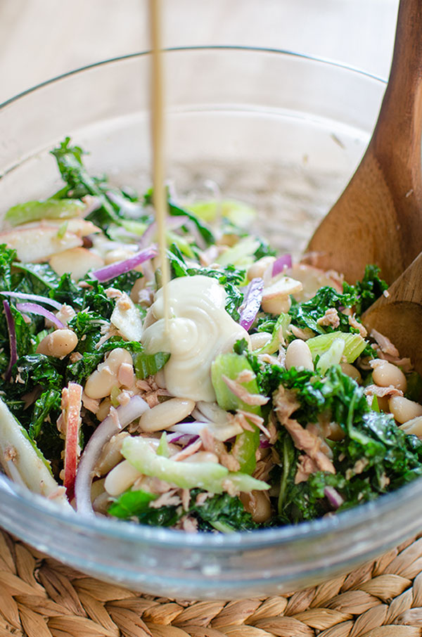 Closeup of salad in a bowl with tahini dressing being poured over top
