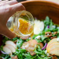 Apple cider vinegar dressing being poured onto a salad