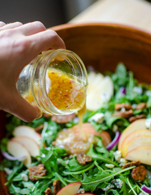 Apple cider vinegar dressing being poured onto a salad