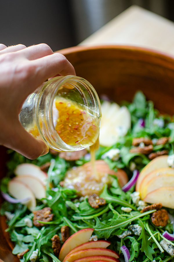 Apple cider vinegar dressing being poured onto a salad