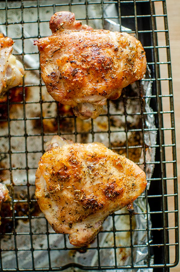 Perfectly roasted chicken thighs on a baking sheet.