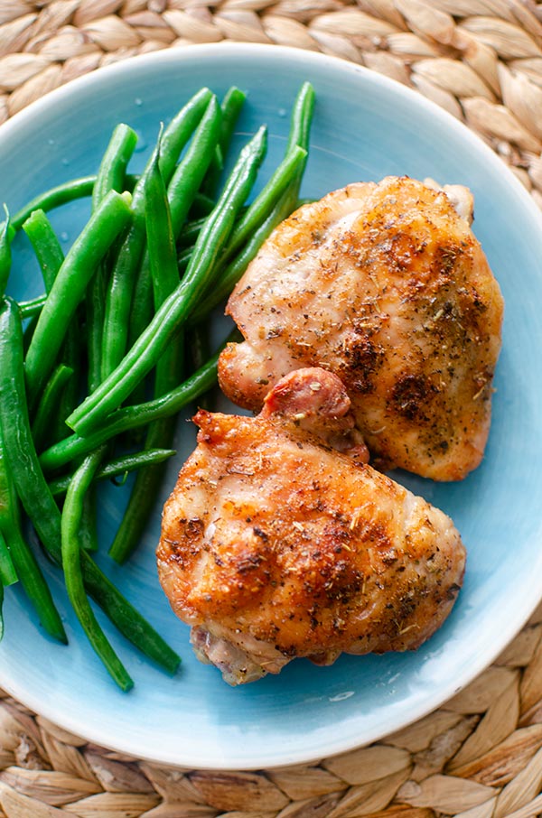 crispy roasted chicken thighs on a plate with green beans.