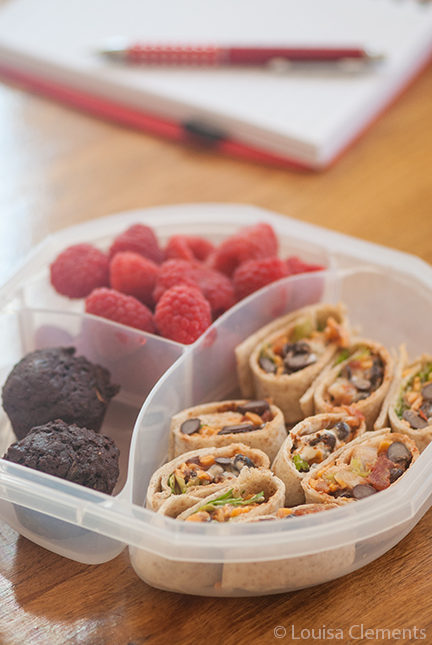 vegetarian-taco-wraps in a lunchbox with raspberries and chocolate muffins