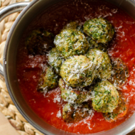 Turkey spinach meatballs in marinara sauce in a pot with parmesan cheese on top.