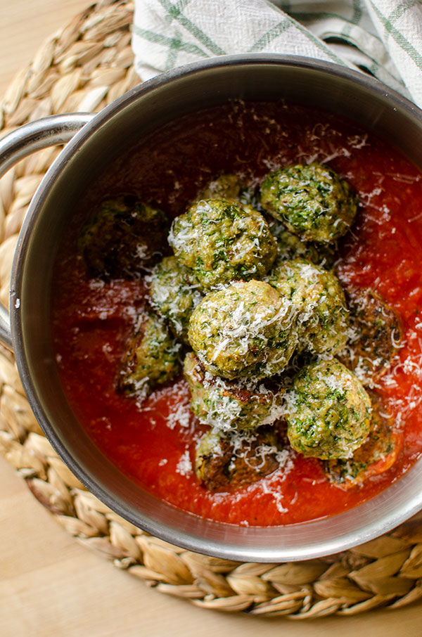 Turkey spinach meatballs in marinara sauce in a pot with parmesan cheese on top.