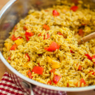 Bell pepper rice in a stainless steel saute pan with a wooden spoon