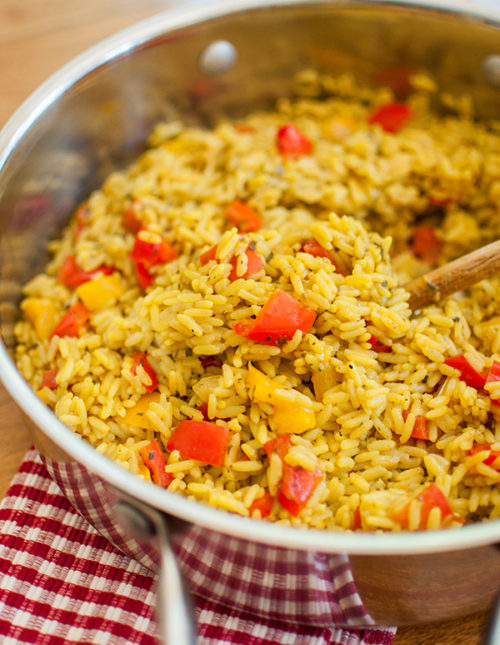 Bell pepper rice in a stainless steel saute pan with a wooden spoon