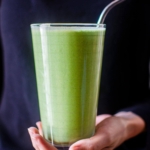 A serving of smoothie in a glass being held by a person