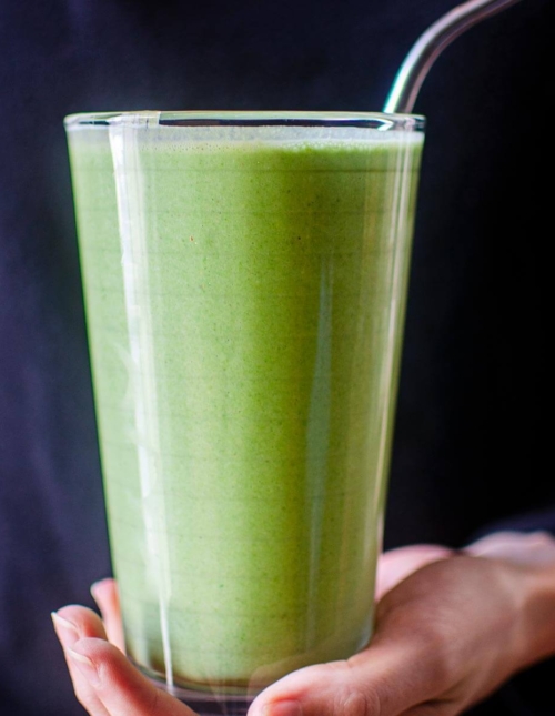 A serving of smoothie in a glass being held by a person