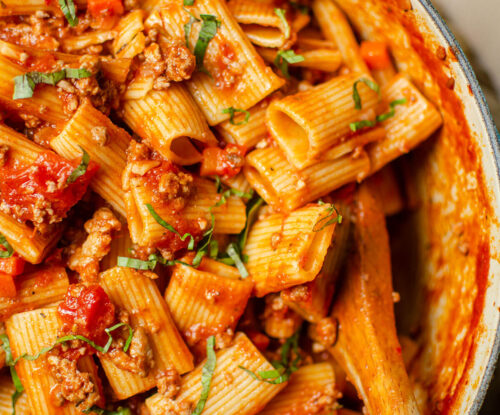 Closeup of rigatoni bolognese in a Dutch oven.