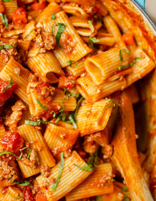 Closeup of rigatoni bolognese in a Dutch oven.