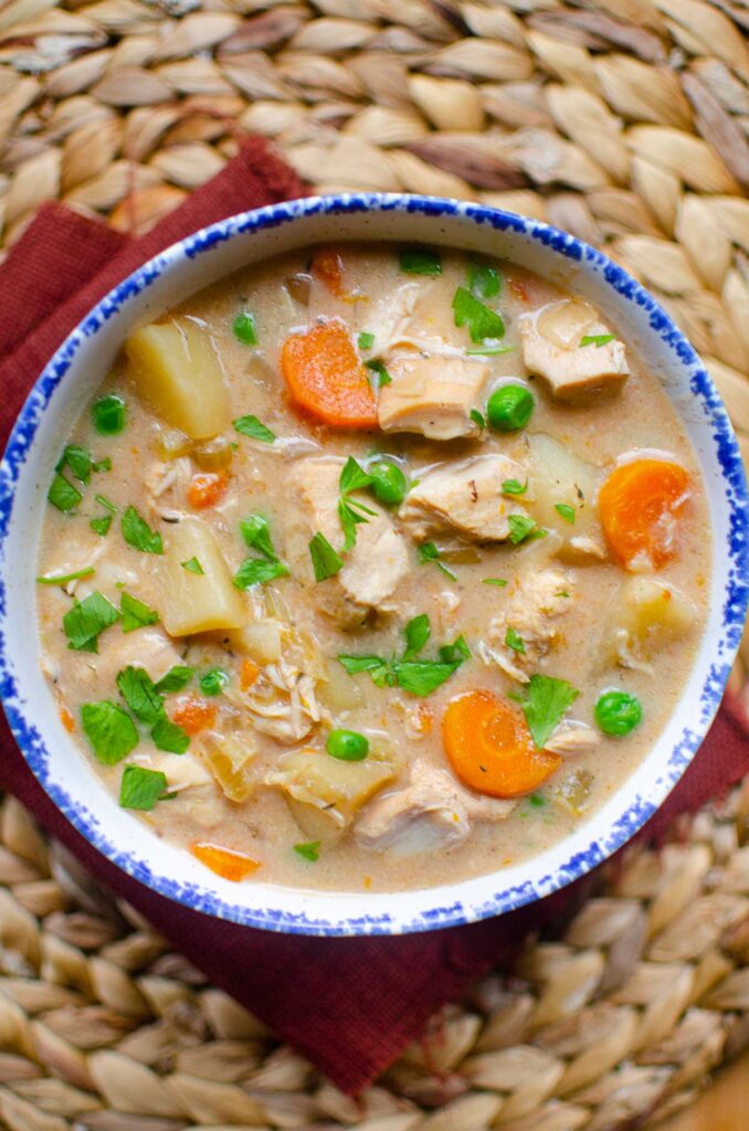 A serving of chicken stew in a bowl with a blue rim.