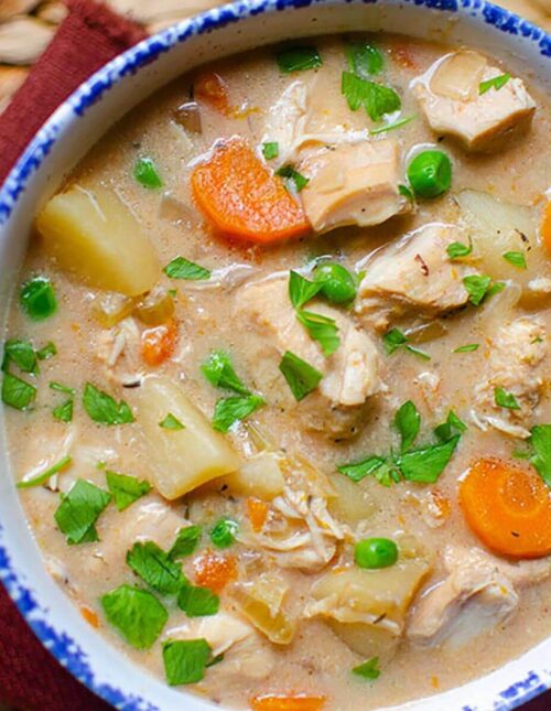 Closeup of a serving of stew in a white bowl with a blue rim.