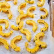 A sheetpan of sliced, roasted delicata squash.