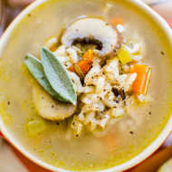 A bowl of turkey rice soup with fresh sage garnish