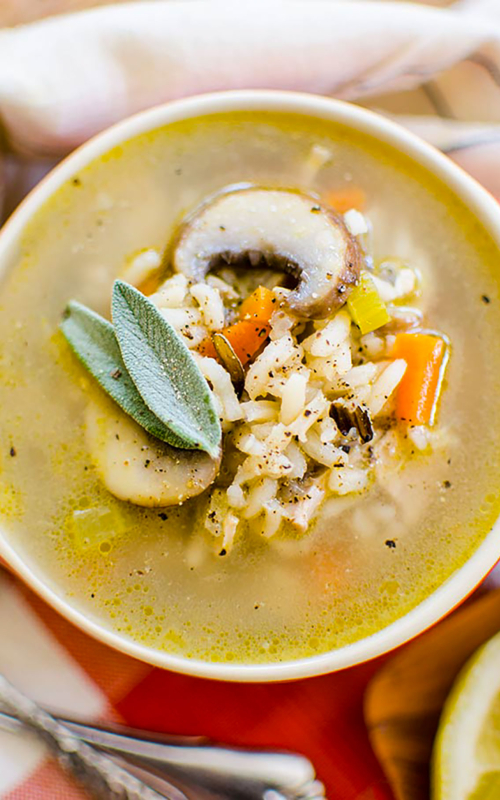 A bowl of turkey rice soup with fresh sage garnish