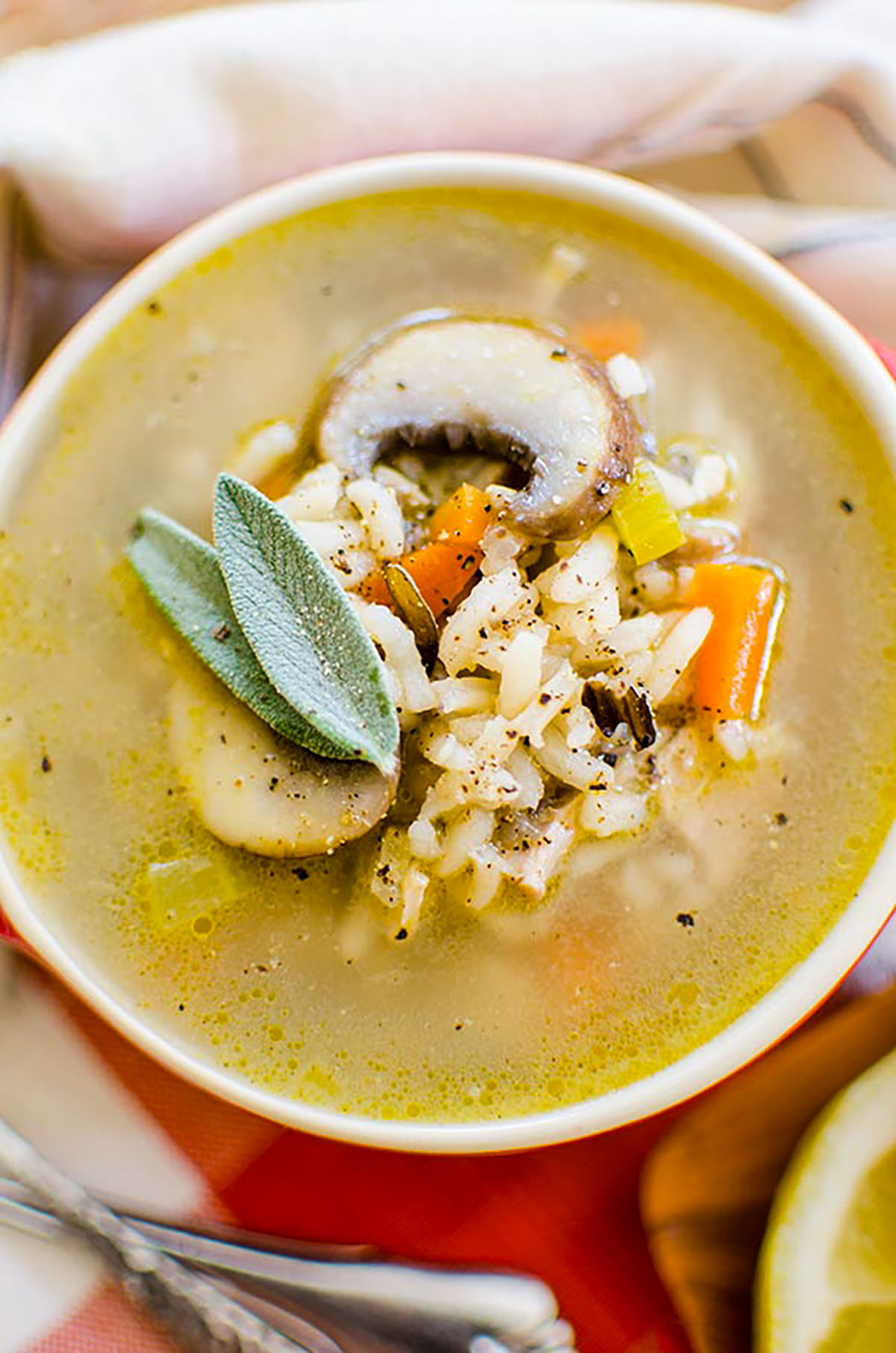 A bowl of turkey rice soup with fresh sage garnish