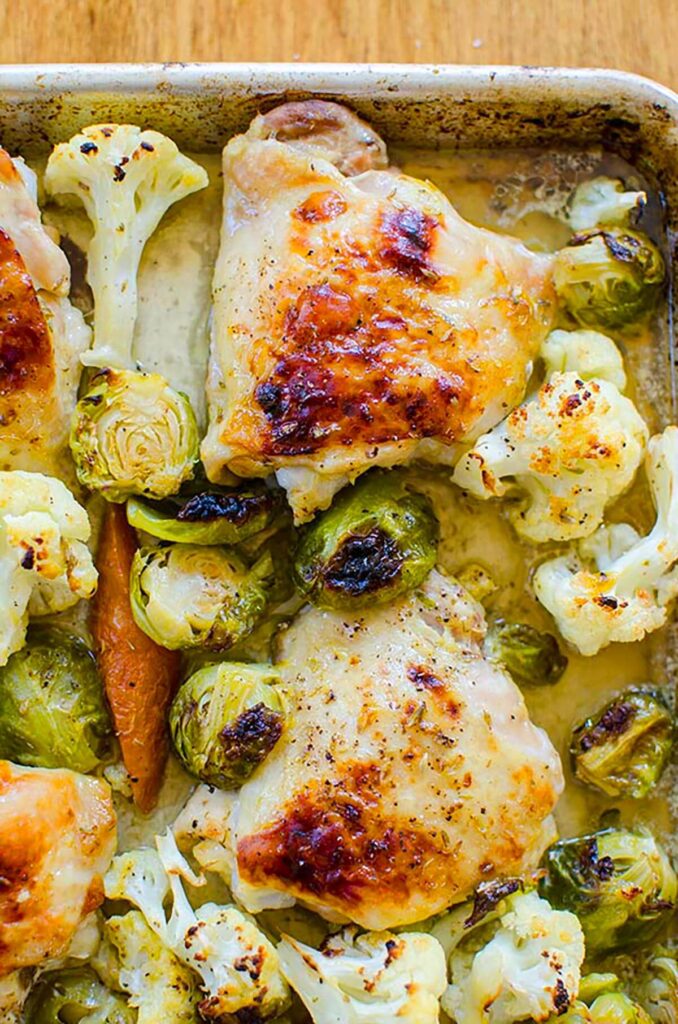 Closeup of browned chicken and vegetables on a sheet pan.