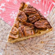 A slice of pecan pie cheesecake on a glass plate.