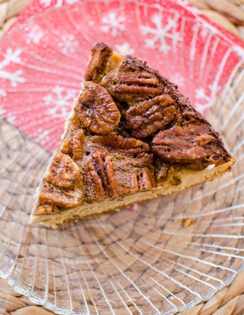 A slice of pecan pie cheesecake on a glass plate.
