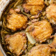 Crispy braised chicken thighs in a pot with mushrooms, white beans, cabbage and bacon