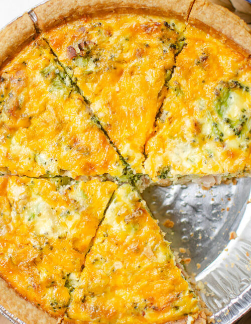 Closeup of broccoli bacon quiche cut into slices with a slice missing.