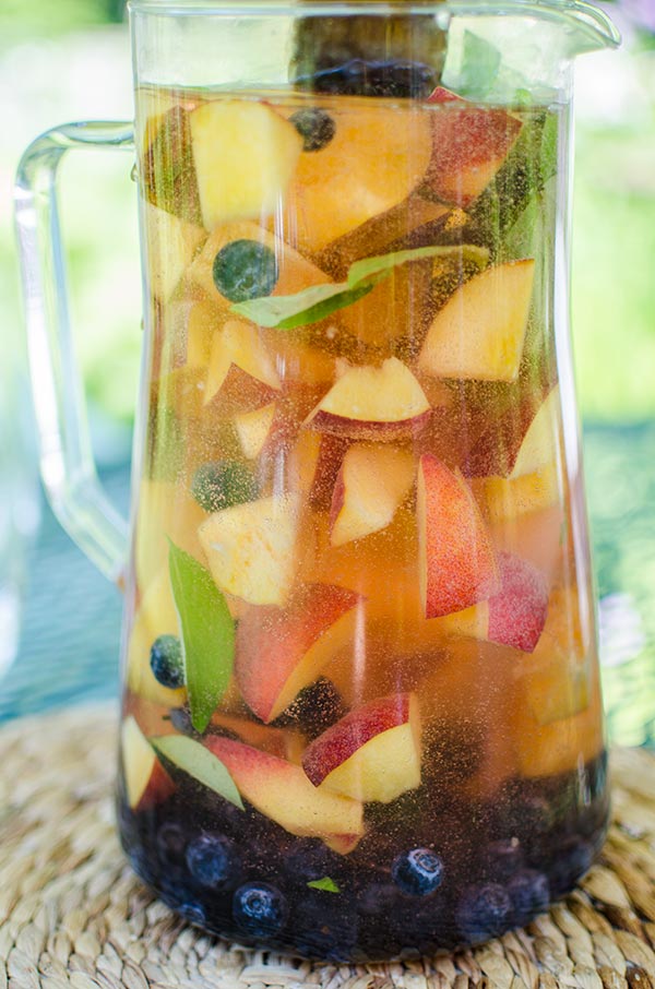 Peach sangria with blueberries, basil and rose for a crowd for a refreshing summer cocktail. | livinglou.com 